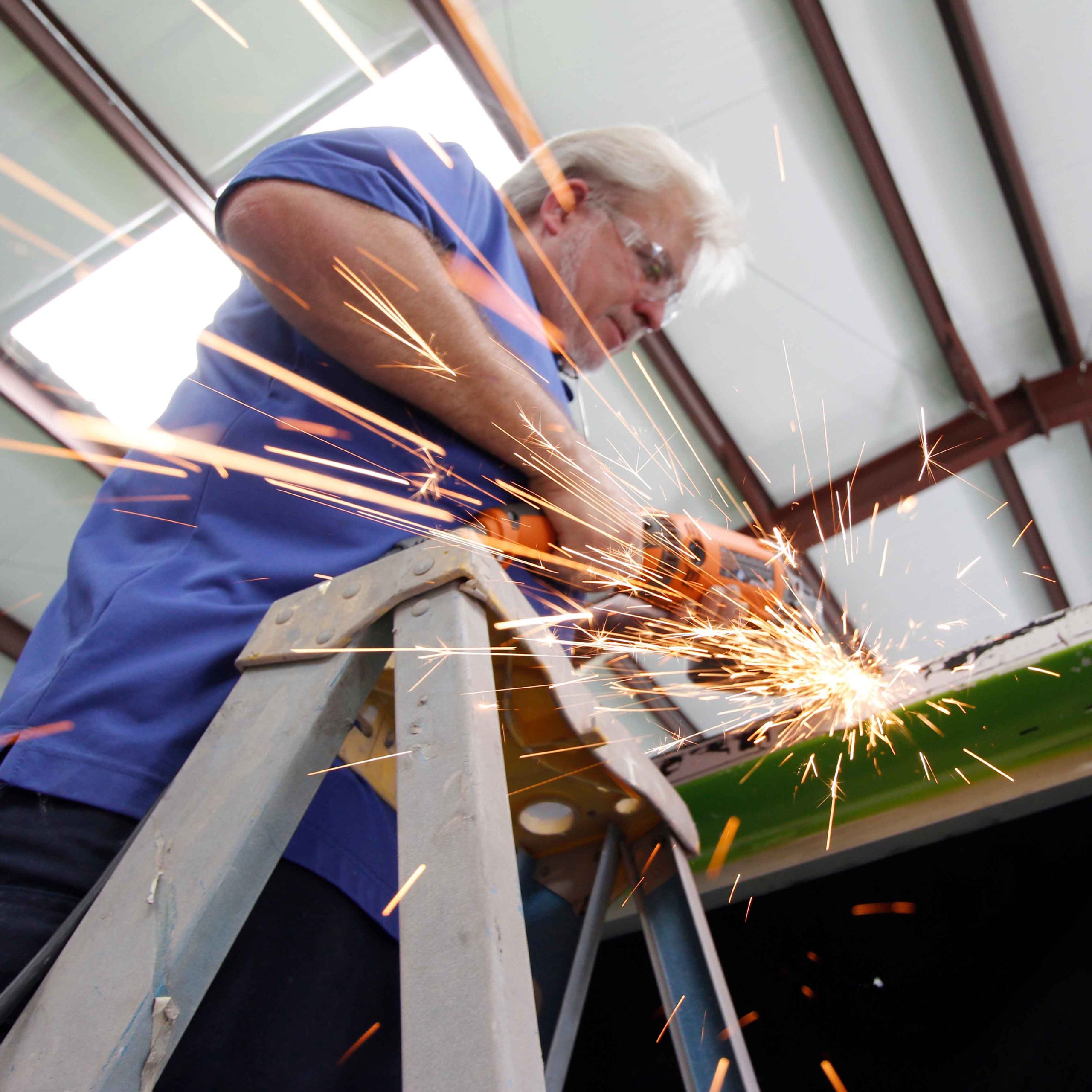 man working at a body shop with sparks flying as he works with metal