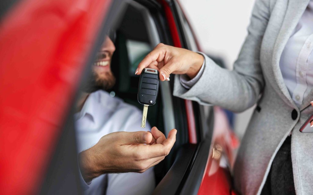 woman handing the keys of a vehicle over to man driving car